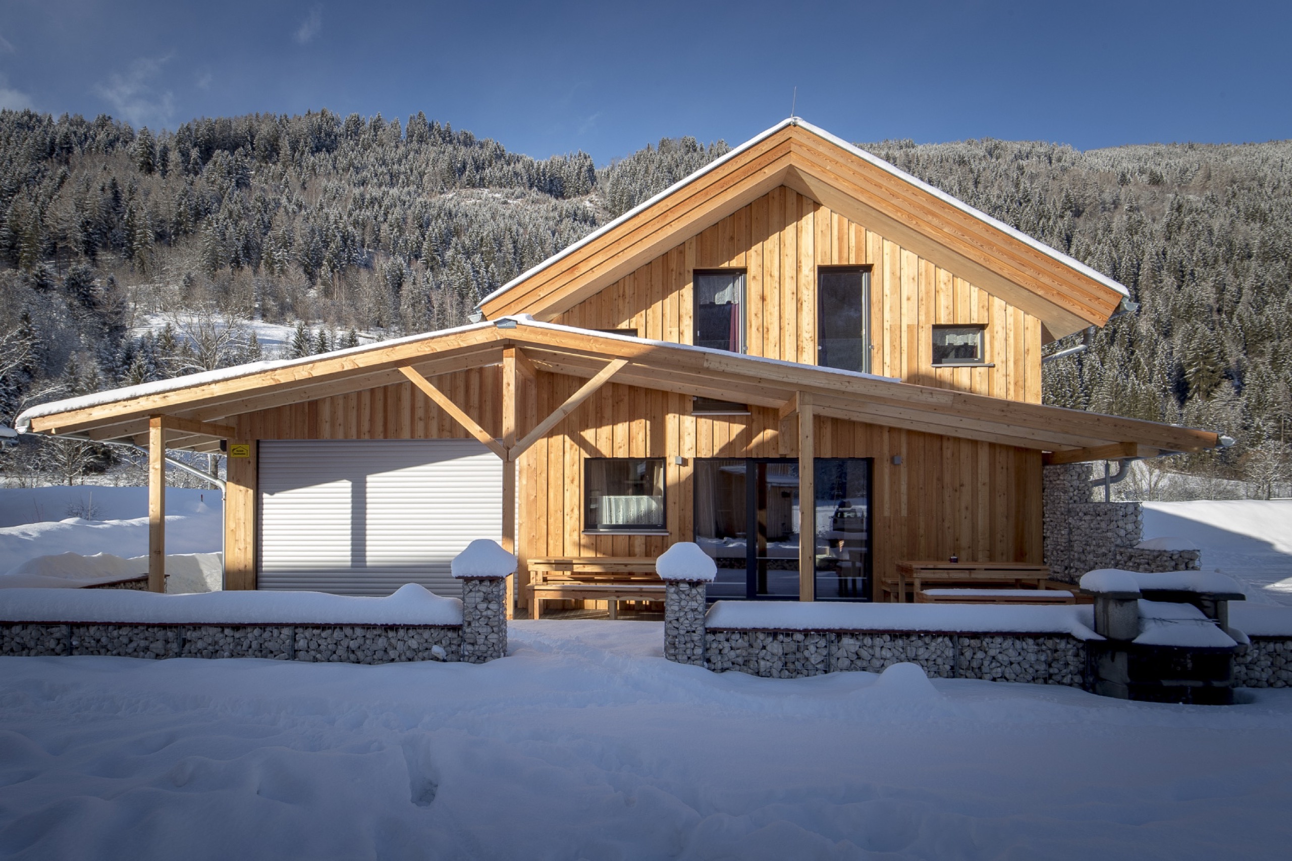 Frontansicht des Chalets mit Holzterrasse im Schnee