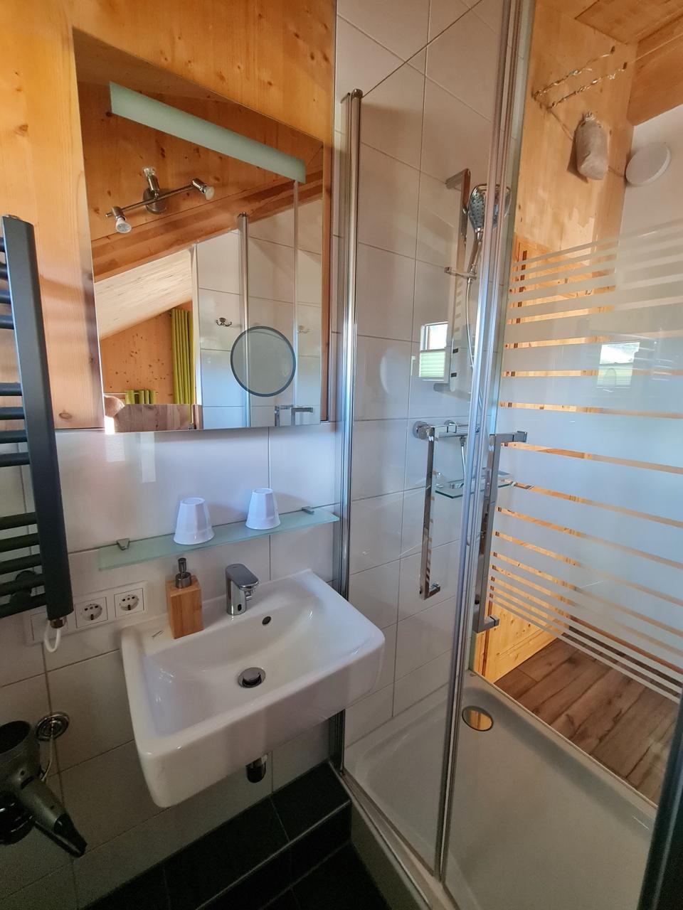 Bad mit Glasdusche, Waschtisch und Holzvertäfelung